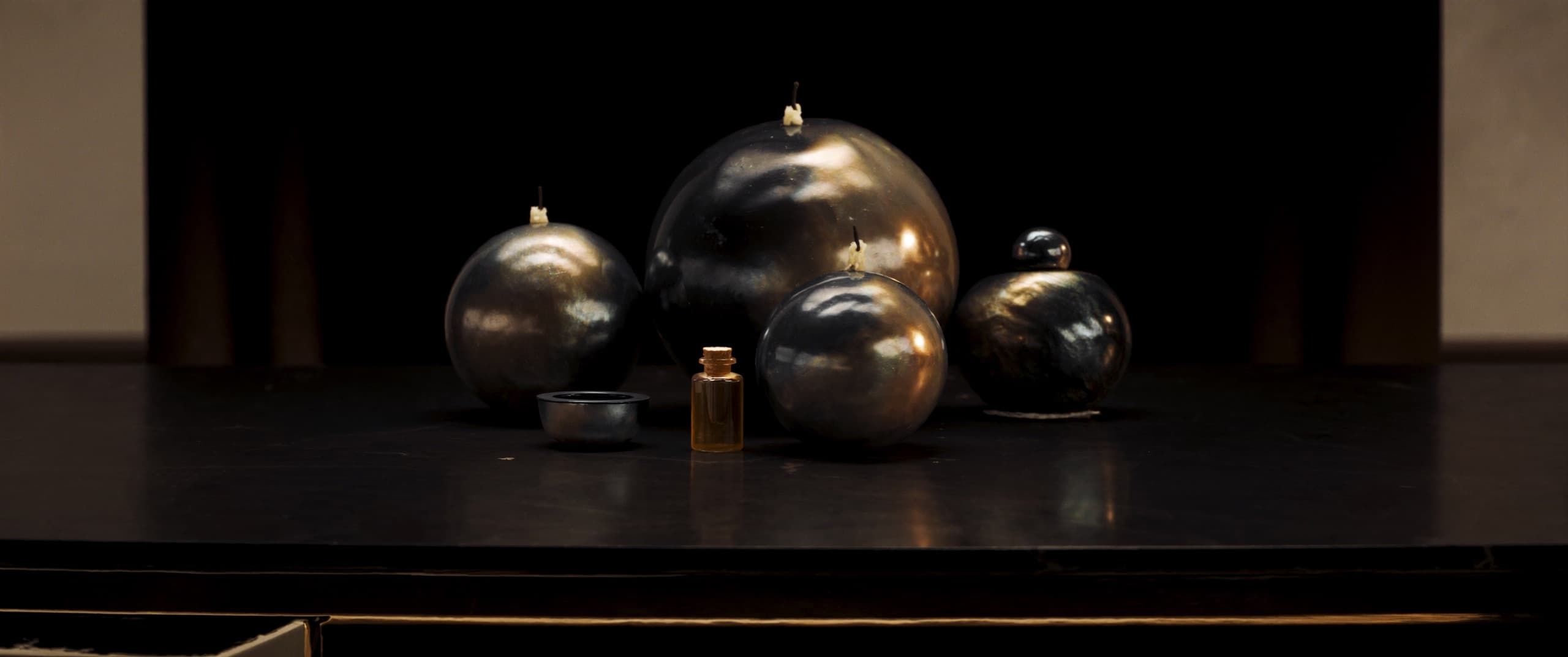 Sphères de verre nacré sombre sur pierre noire polie, lumière chaude