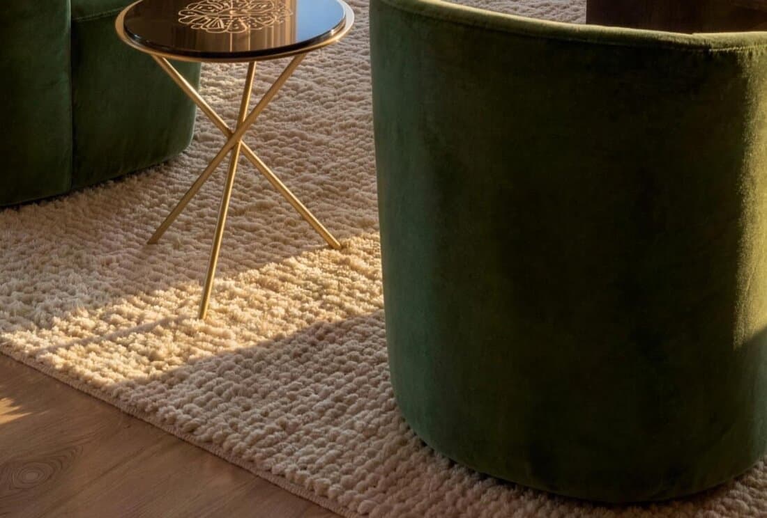 Tapis en laine bouclée sous un guéridon en laiton et des fauteuils en velours